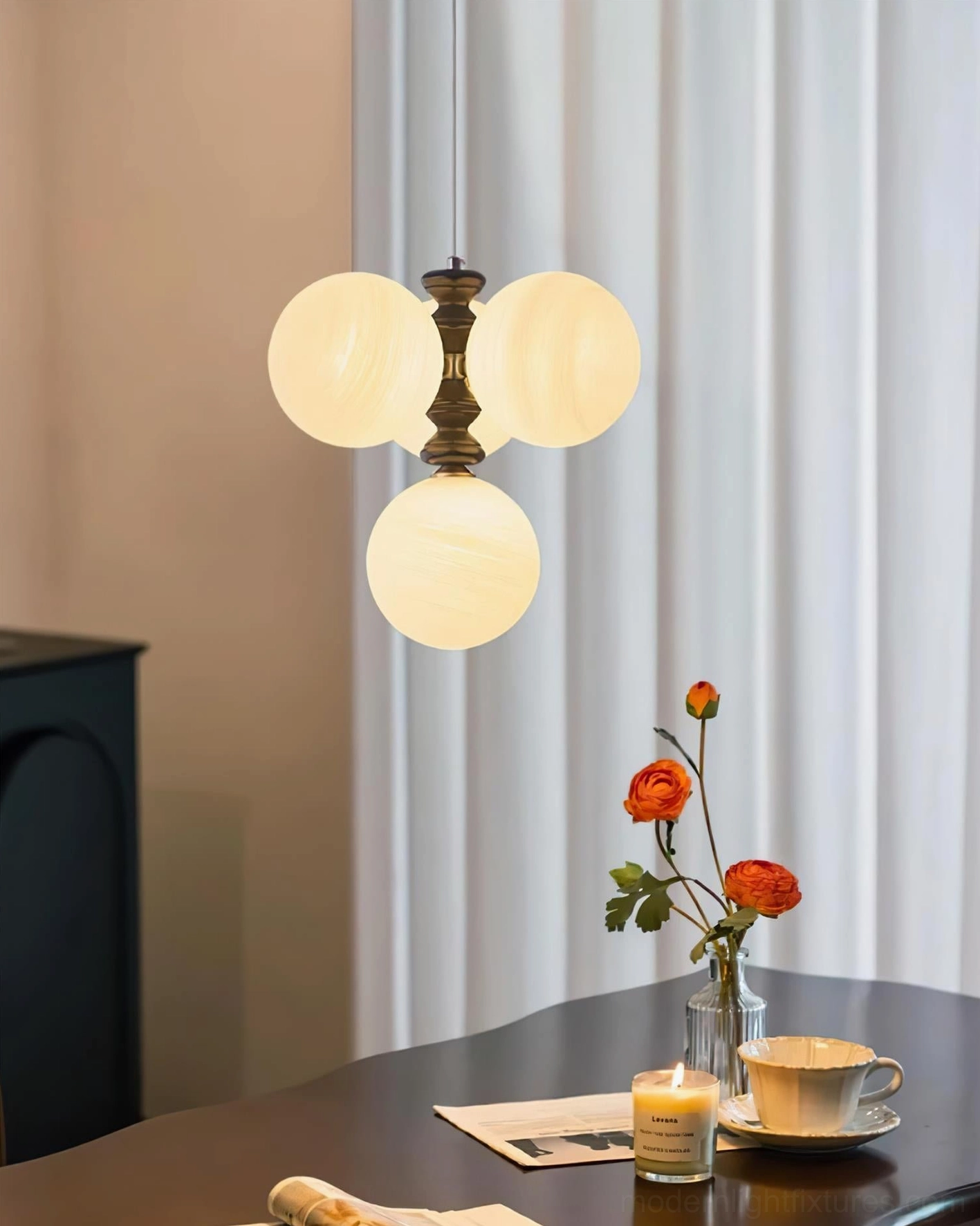 Sloane arc pendant light with brass hardware and warm frosted glass shades above dining table