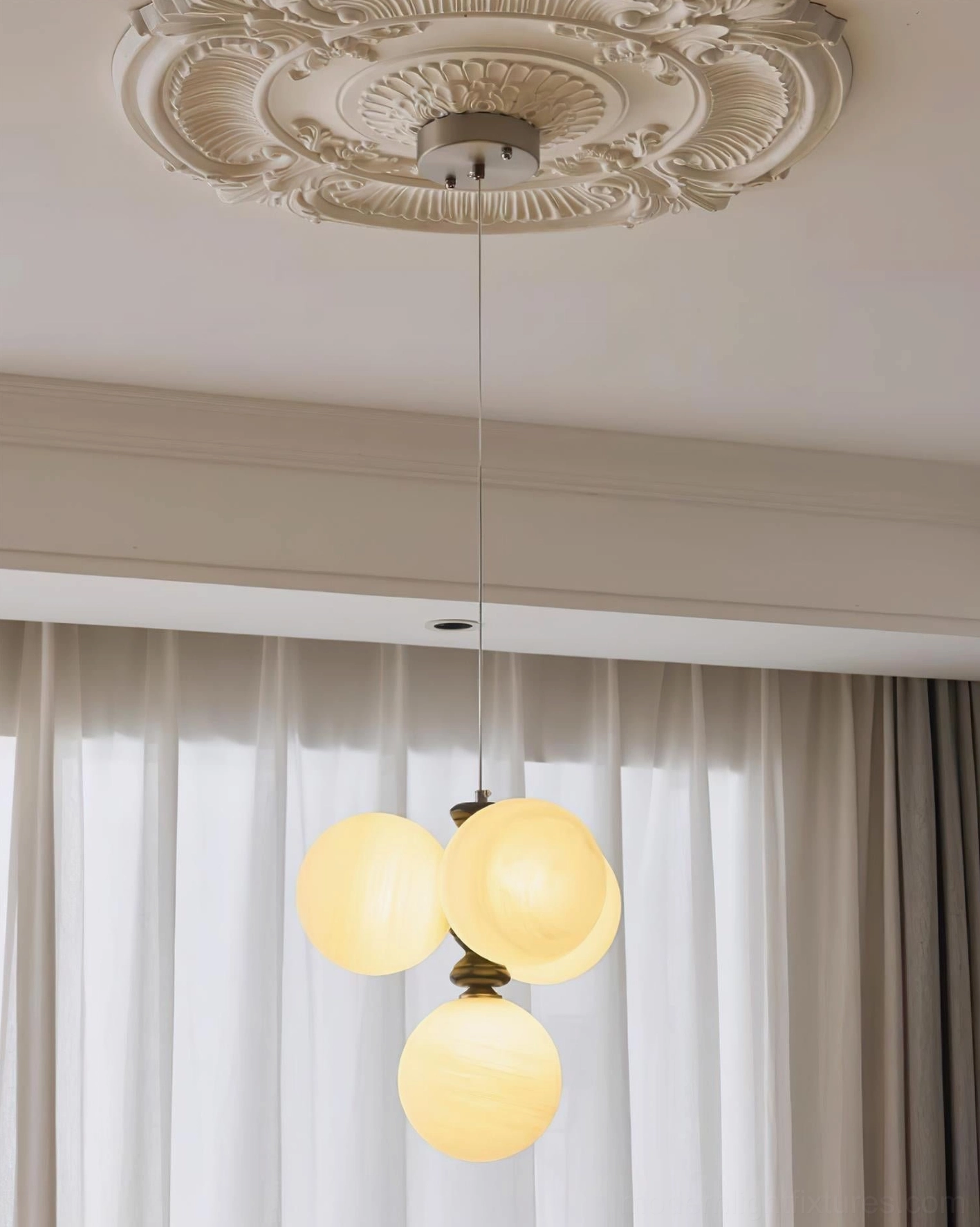 Arc pendant fixture with warm yellow spherical glass shades in dining area with sheer curtains