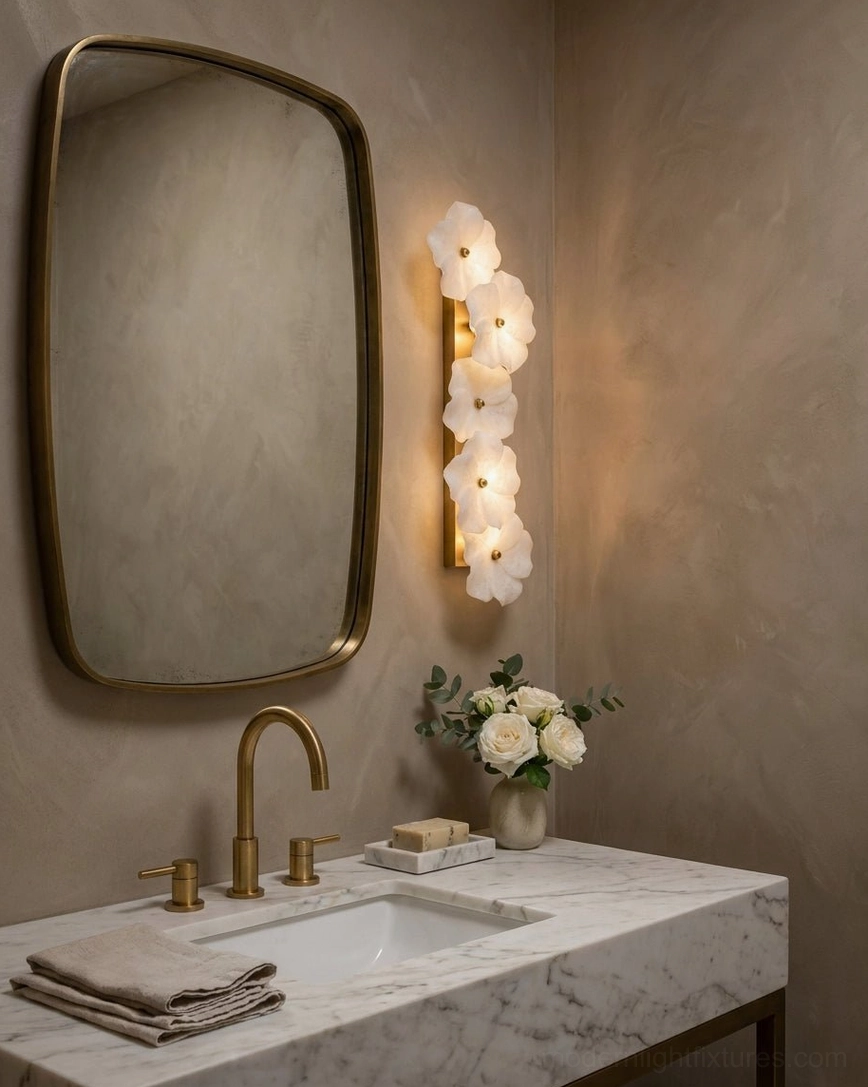 Small Alabaster Bloom Wall Sconce illuminated above bathroom vanity, warm white brass hardware