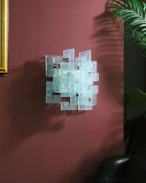 Solvante cyan glass wall lamp mounted on burgundy accent wall, unlit stacked glass block design, side perspective