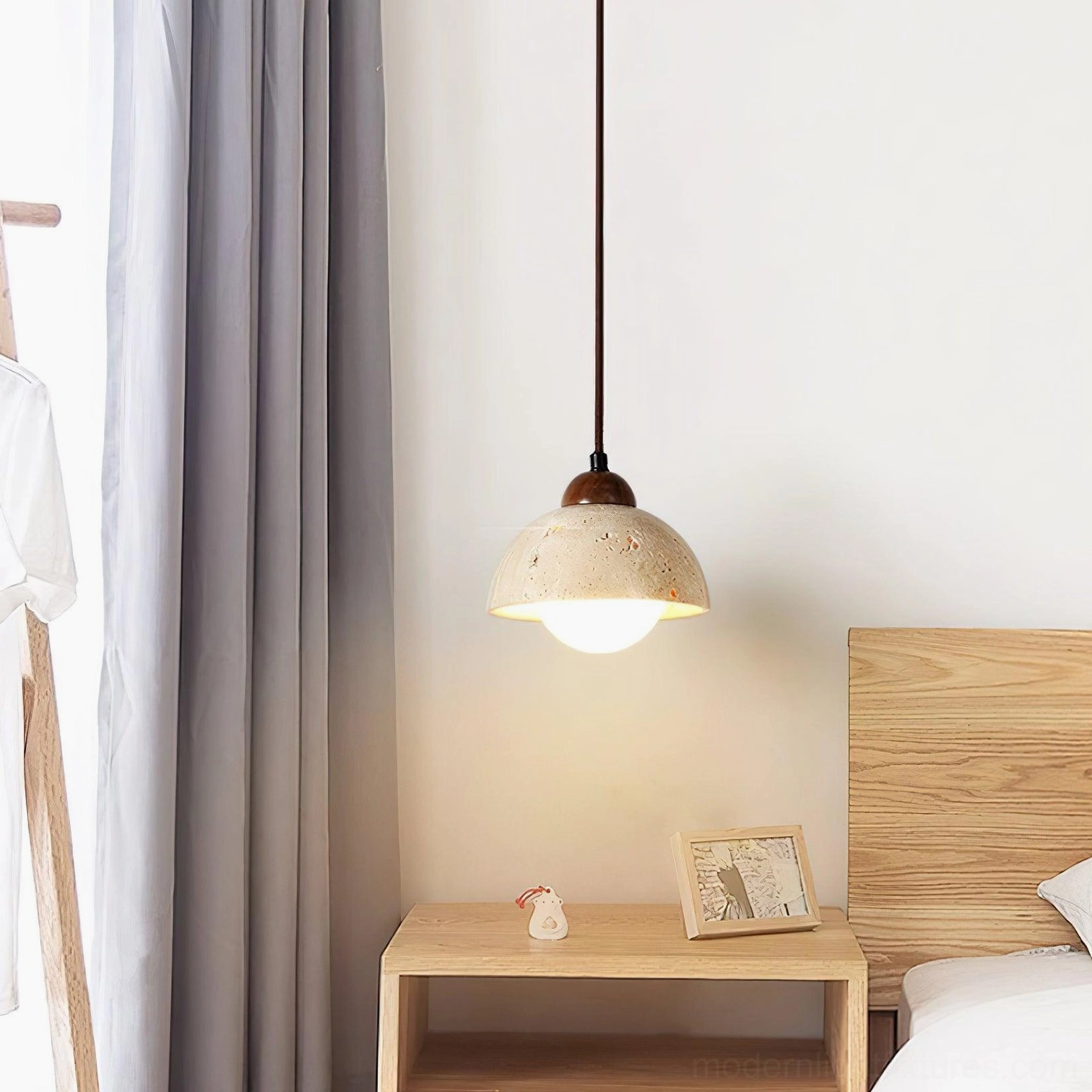 Soren travertine pendant light hung above minimalist wooden bedside table in modern bedroom