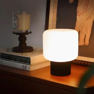 Contemporary sphere table lamp with black ribbed base on bedroom nightstand with candles and books
