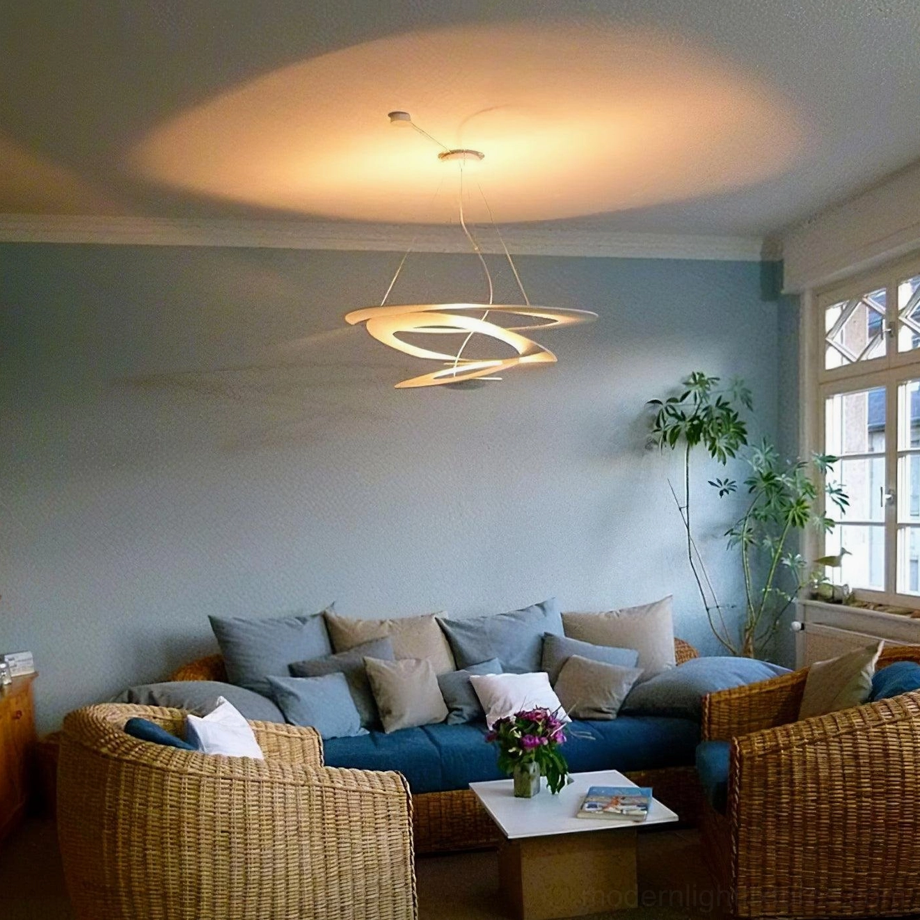 Spiral LED pendant light side view in residential living room, matte white structure with warm yellow task lighting