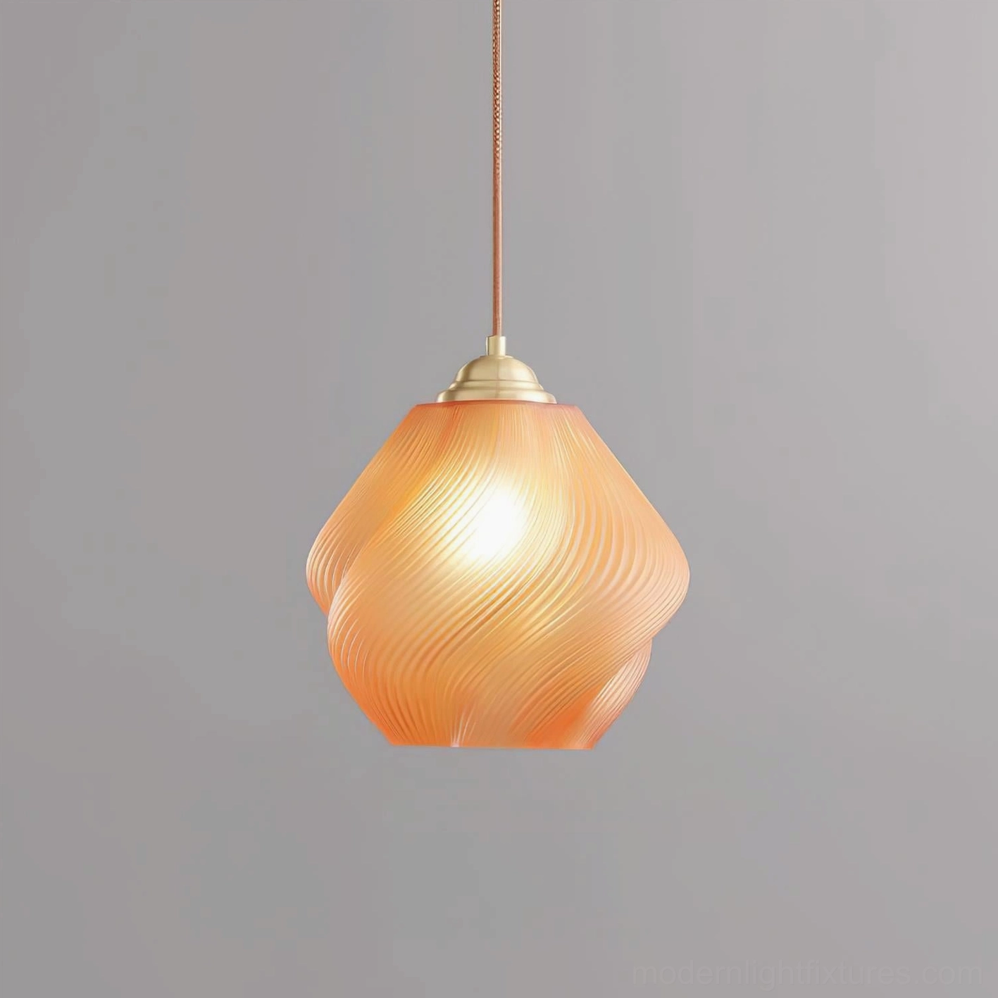 Spirvia orange twisted hand-blown glass pendant light - vibrant orange swirled ribbed texture studio close-up with brass components