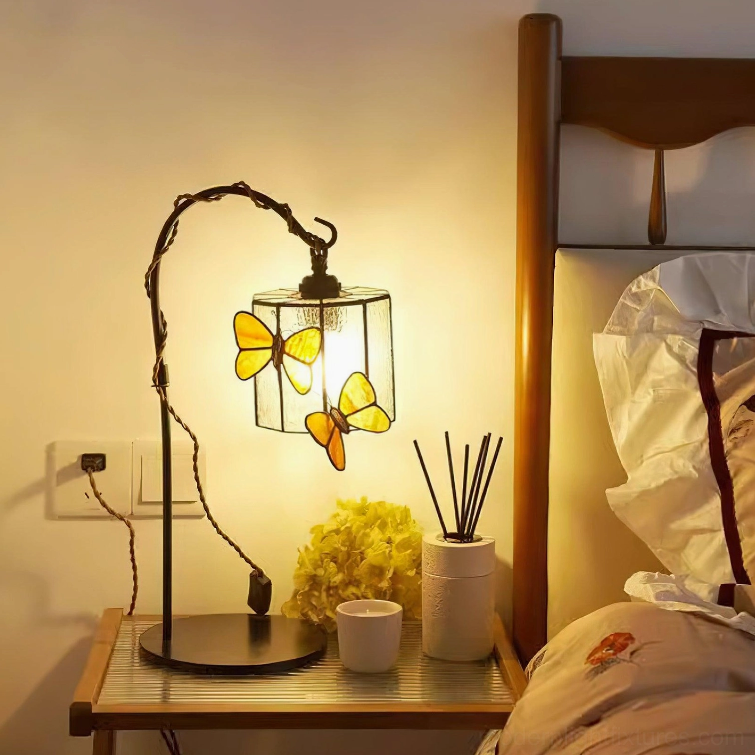 Square stained glass butterfly lamp with black stand on wooden nightstand in cozy bedroom setting