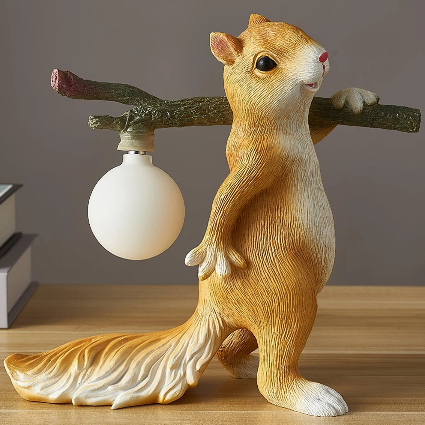 Orange and white squirrel lamp on wooden table, showing detailed resin fur texture and spherical frosted bulb