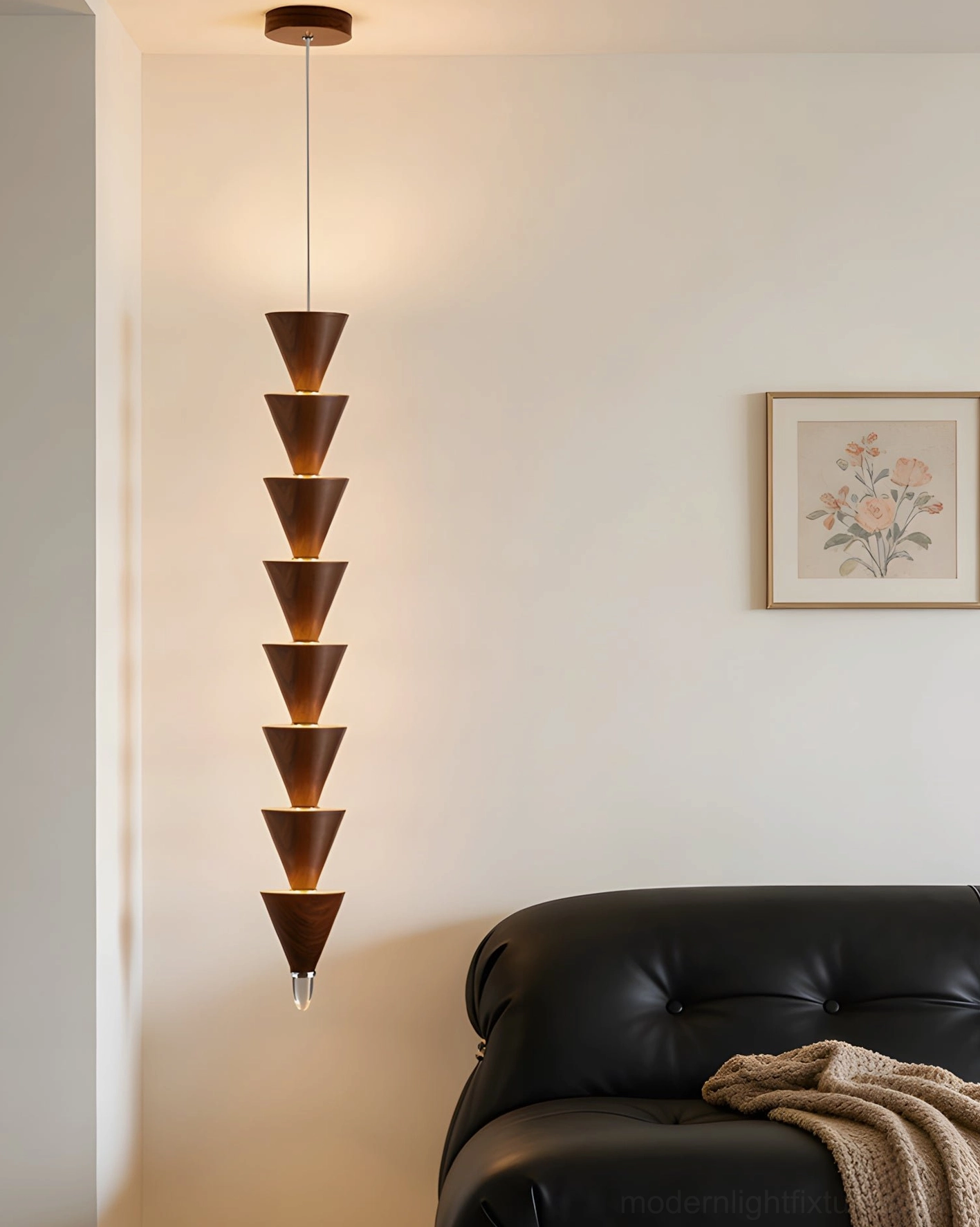 Contemporary stacked cone pendant light illuminating modern living room above black leather sofa