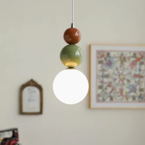 Close-up of three-sphere pendant light showing frosted white globe with terracotta and sage green accent colors