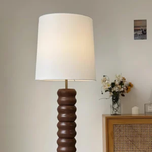 Natural wood stacked floor lamp with white linen shade in residential living room setting