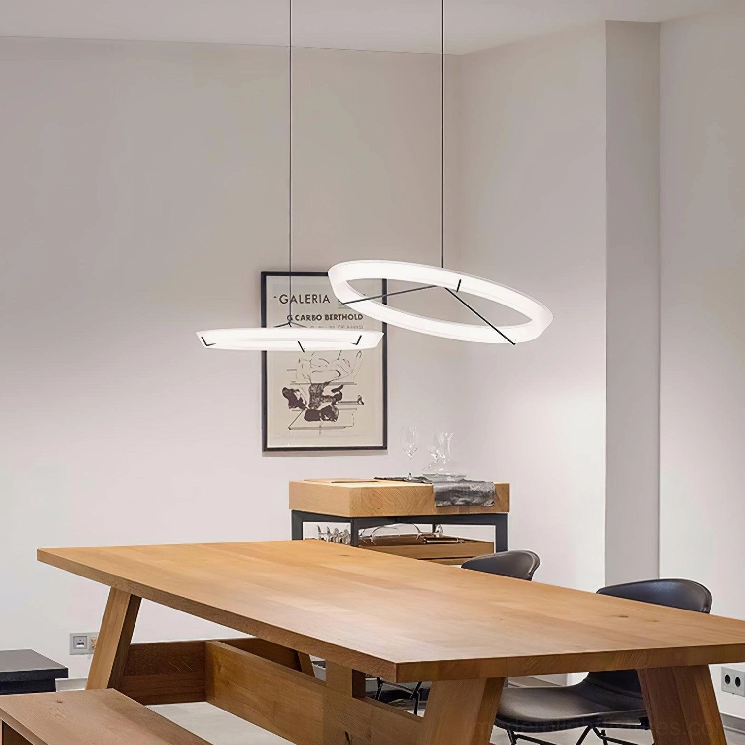 Two staggered round pendant lamps with white glowing rings and black suspension cords over wooden table