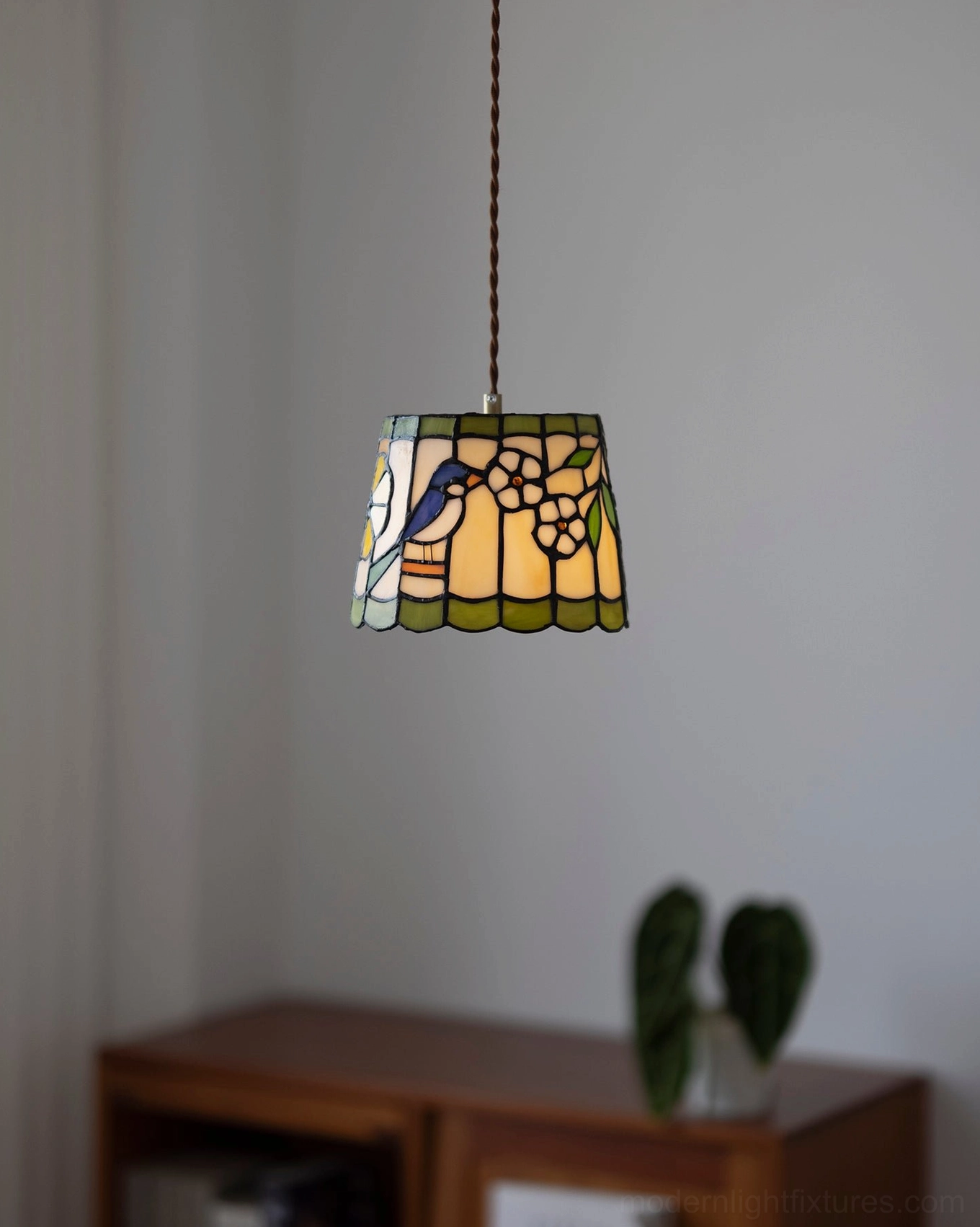 Classic stained glass pendant light with scalloped rim and nature-inspired bird artwork hanging in interior