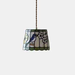 Handcrafted stained glass pendant light with bird and floral design in brass and green, overhead studio view