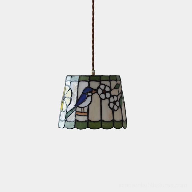 Handcrafted stained glass pendant light with bird and floral design in brass and green, overhead studio view