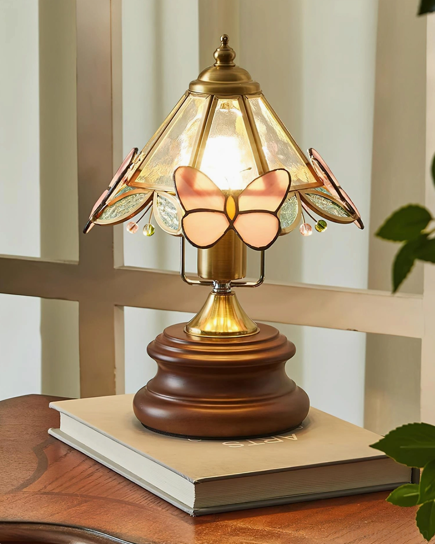 Pink butterfly table lamp three-quarter view revealing frosted art glass and brass hardware on wood base