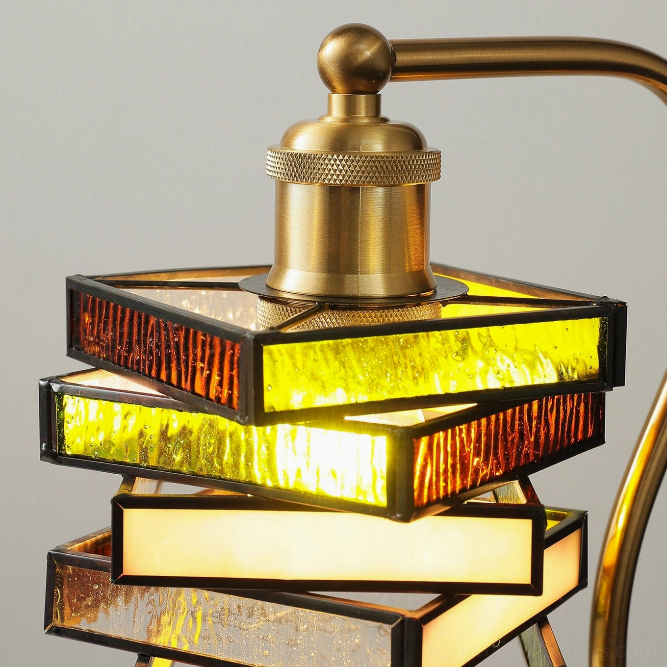Close-up detail of stained glass lamp shade showing textured warm-toned amber and rust colored glass panels and brass socket