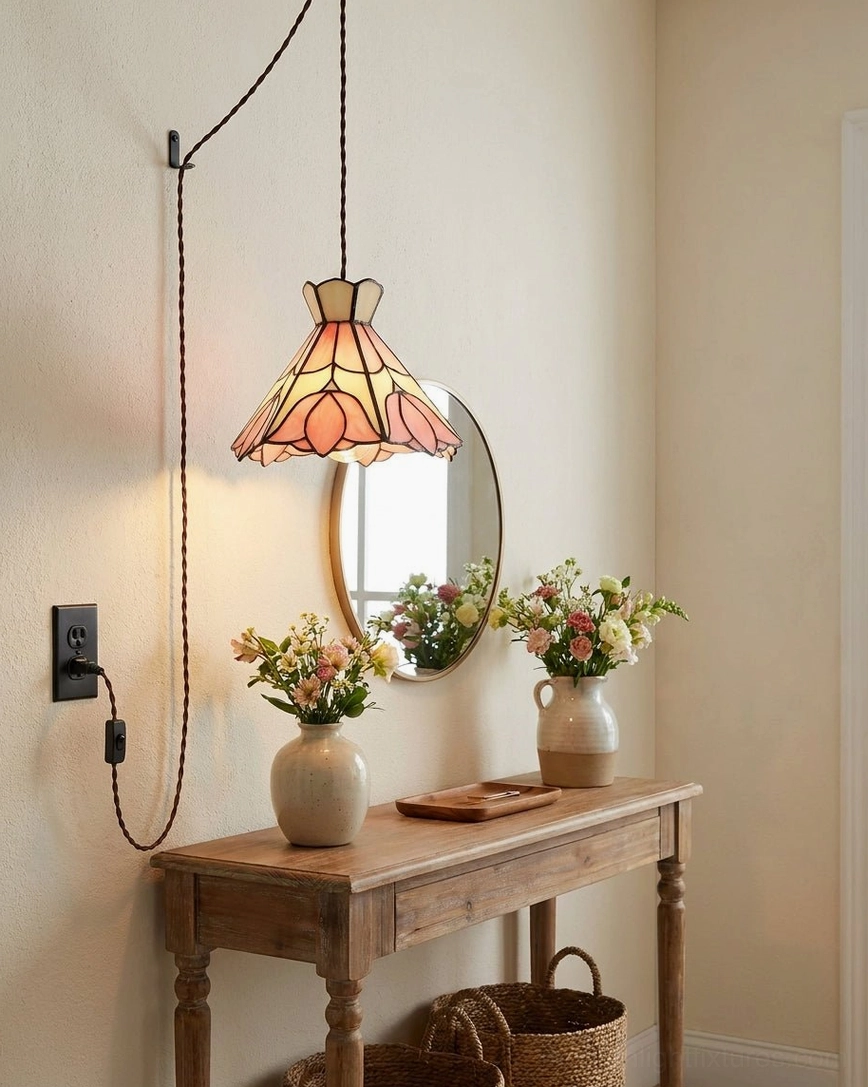 Handmade stained glass lotus pendant hung beside console table with oval mirror and floral arrangement, three-quarter side view of glass shade and soldered seams