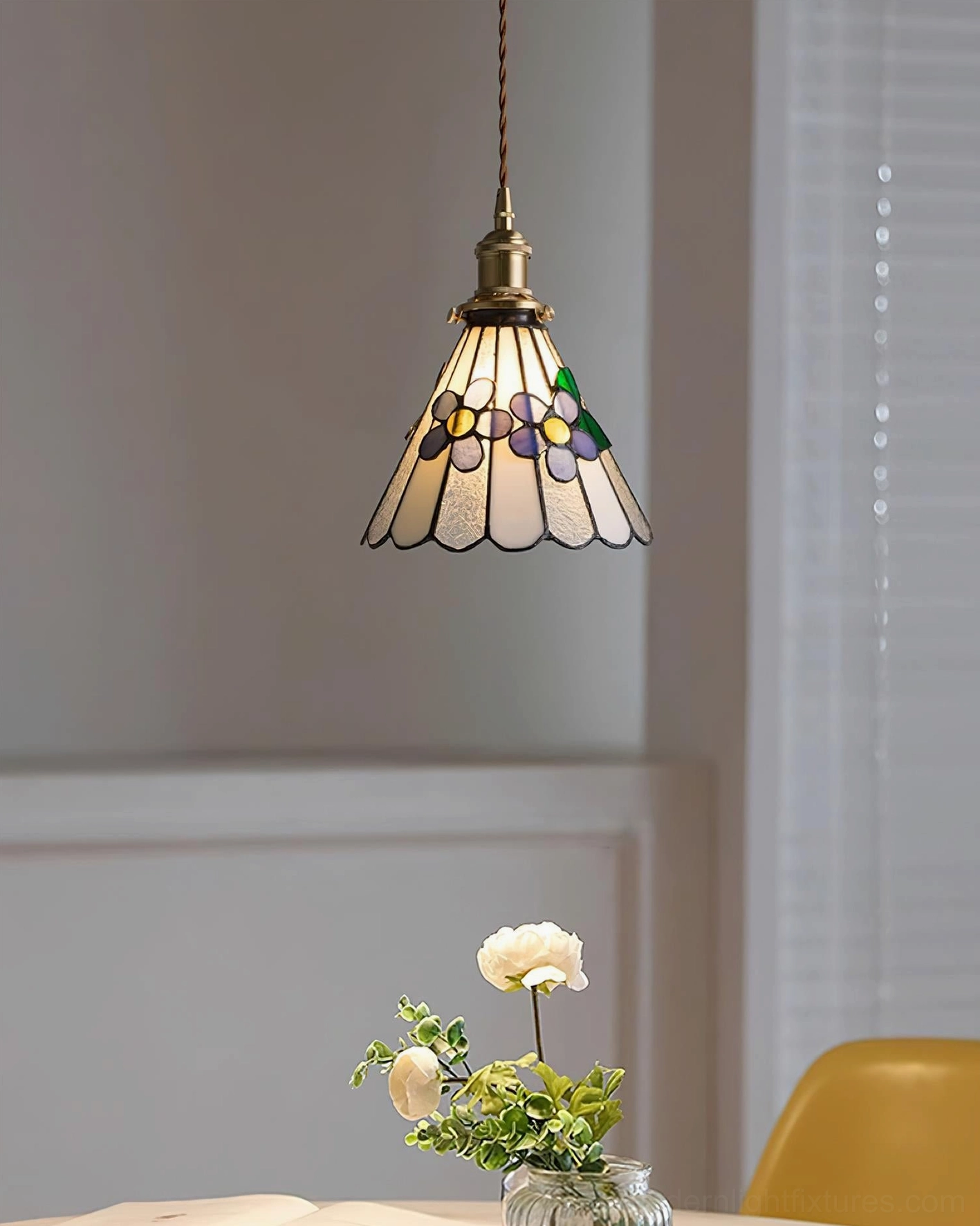 Stained glass pendant light with colorful floral shade illuminated showing jewel-tone glass panel details