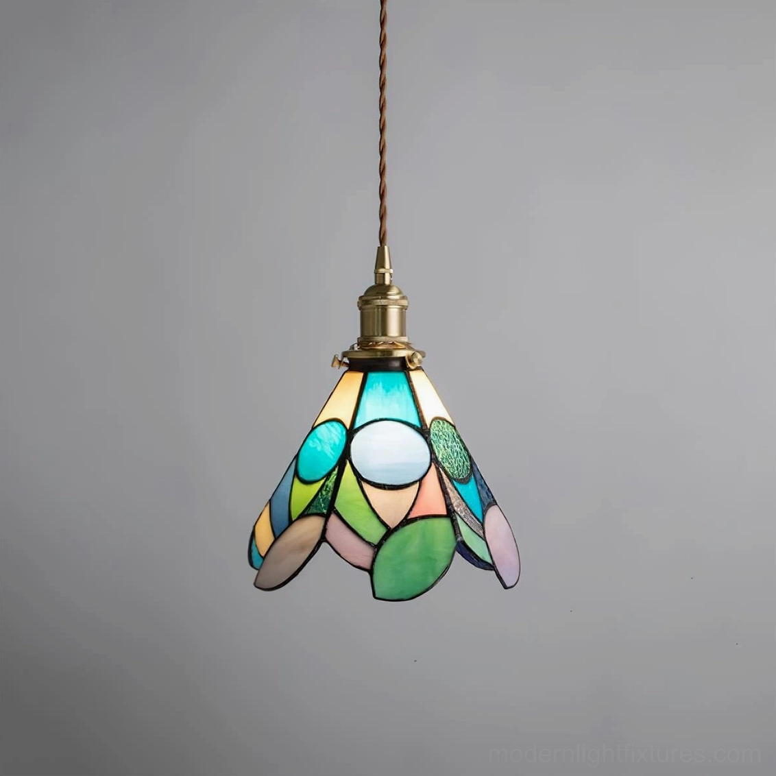 Stained glass pendant light fixture showing geometric panel design and warm amber light diffusion