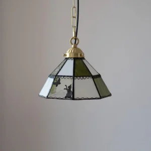 Stained glass pendant light with patchwork green and white glass, hand-applied animal silhouettes, black decorative framing, brass hardware
