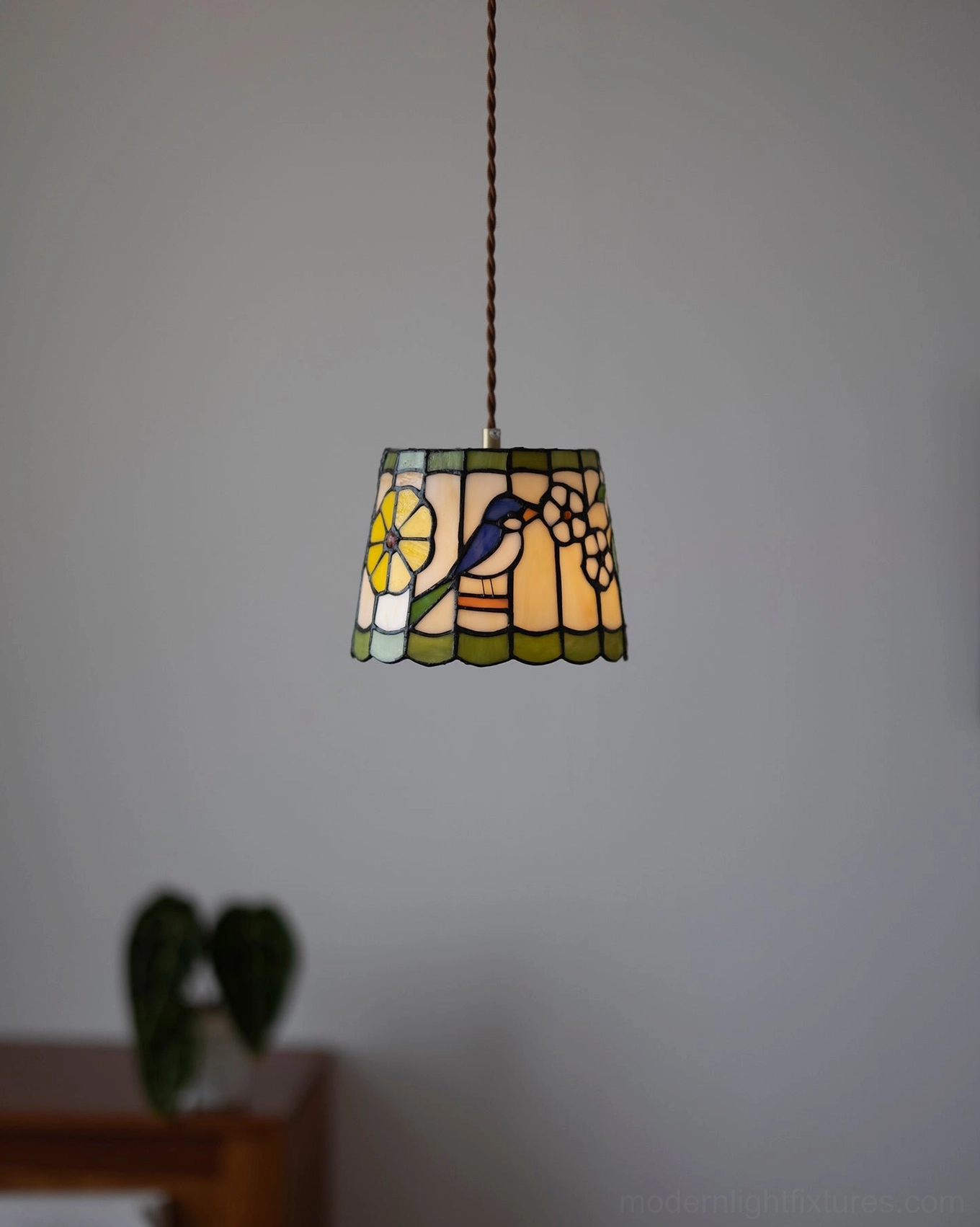 Hand-assembled stained glass pendant lamp with warm amber tones and floral pattern in home setting