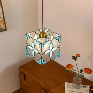 Stained glass pendant lamp three-quarter overhead view - brass hardware and blue floral textured glass shade in residential living room