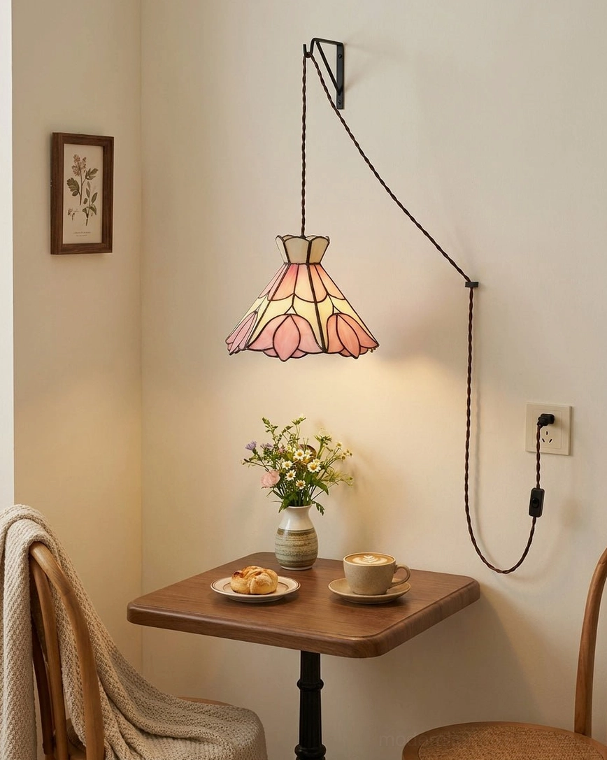 Plug-in stained glass pendant mounted above small dining nook table with wooden furniture, Art Nouveau lotus shade casting warm glow over cottage dining area