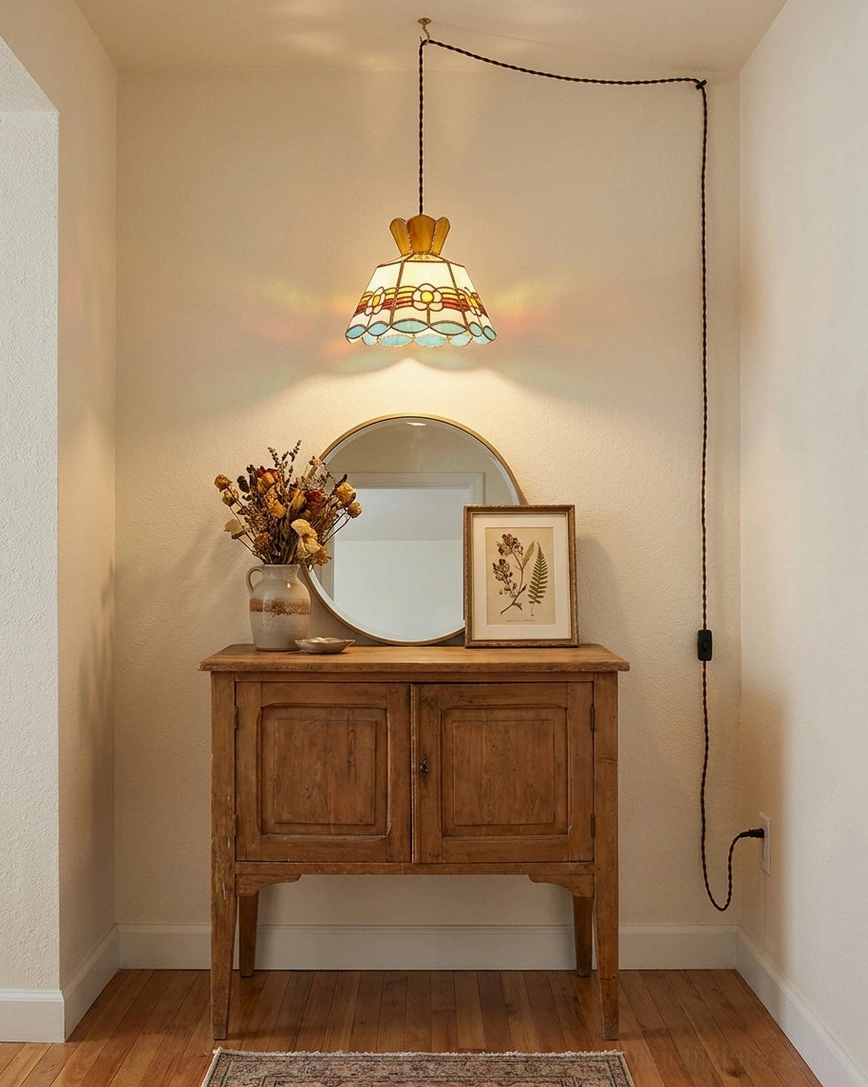 Plug-in stained glass pendant light installed above console table in entryway creating warm multicolor ambient glow with visible copper-foil seams and scalloped art-glass hem
