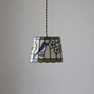 Tiffany-style stained glass pendant light with scalloped edges and artistic bird motif, front angle