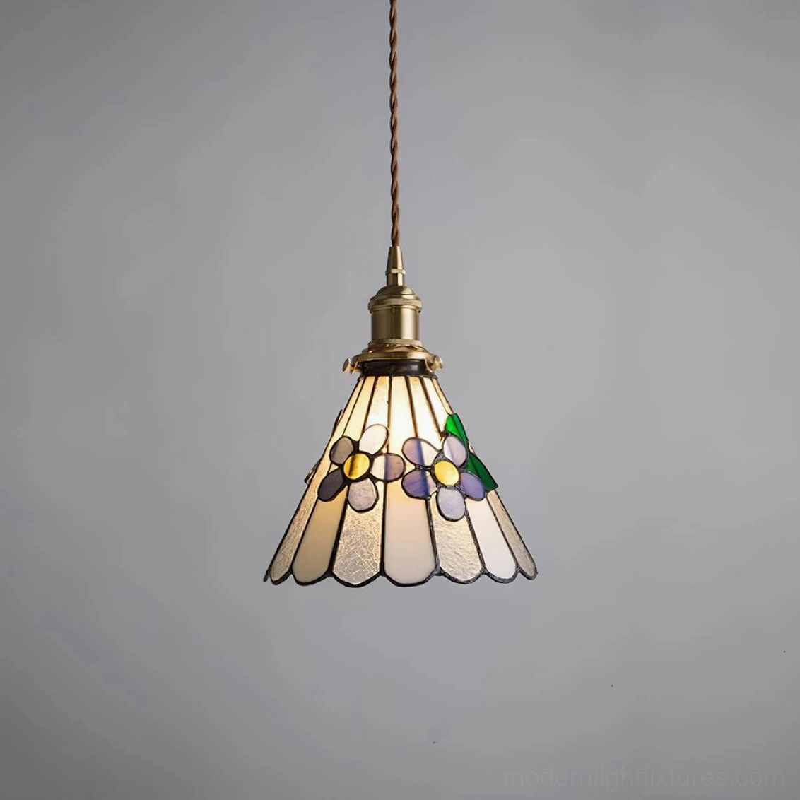 Stained glass pendant lamp with pastel flower design and brass fitting shown in studio lighting