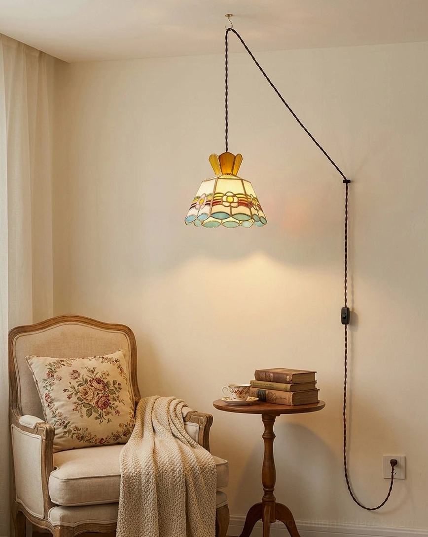 Plug-in stained glass pendant light in living room reading corner with twisted black braided cord creating cozy vintage ambiance over seating area