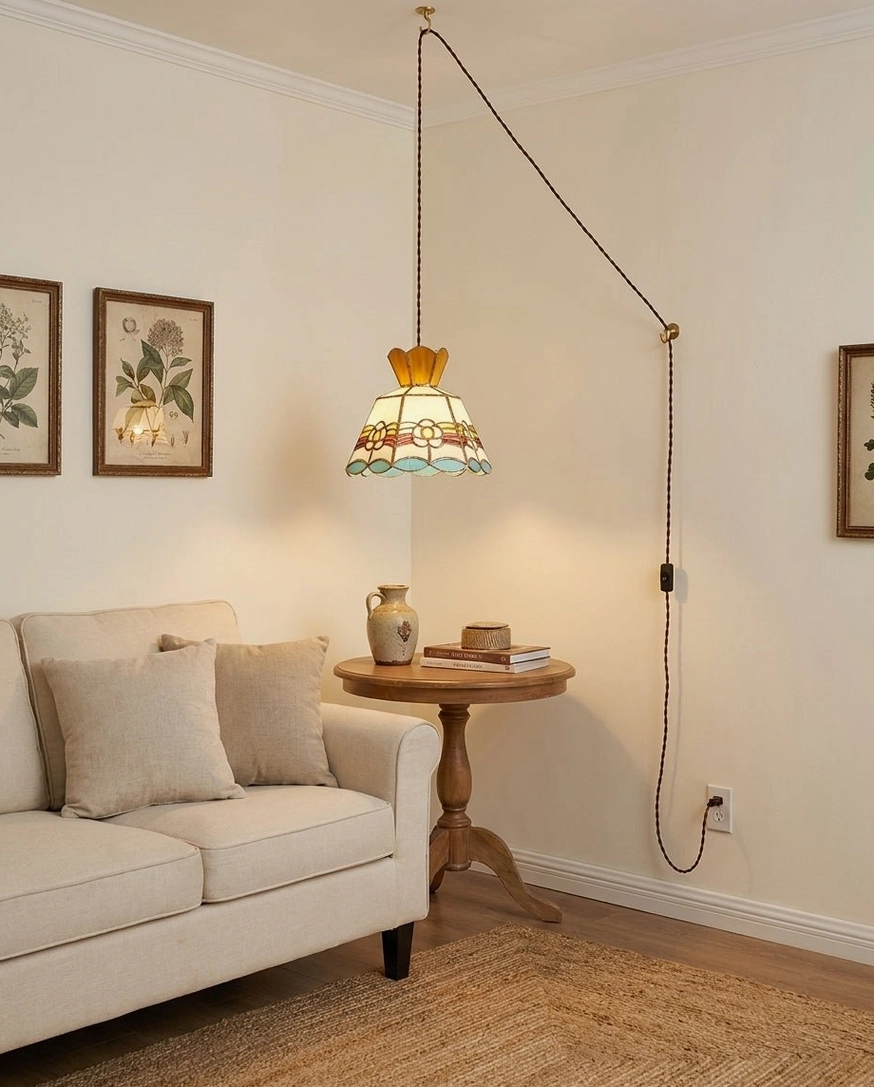 Plug-in pendant light with hand-cut stained glass hanging in sofa lounge area showing exposed braided cord installation and warm multicolor glass glow in living space