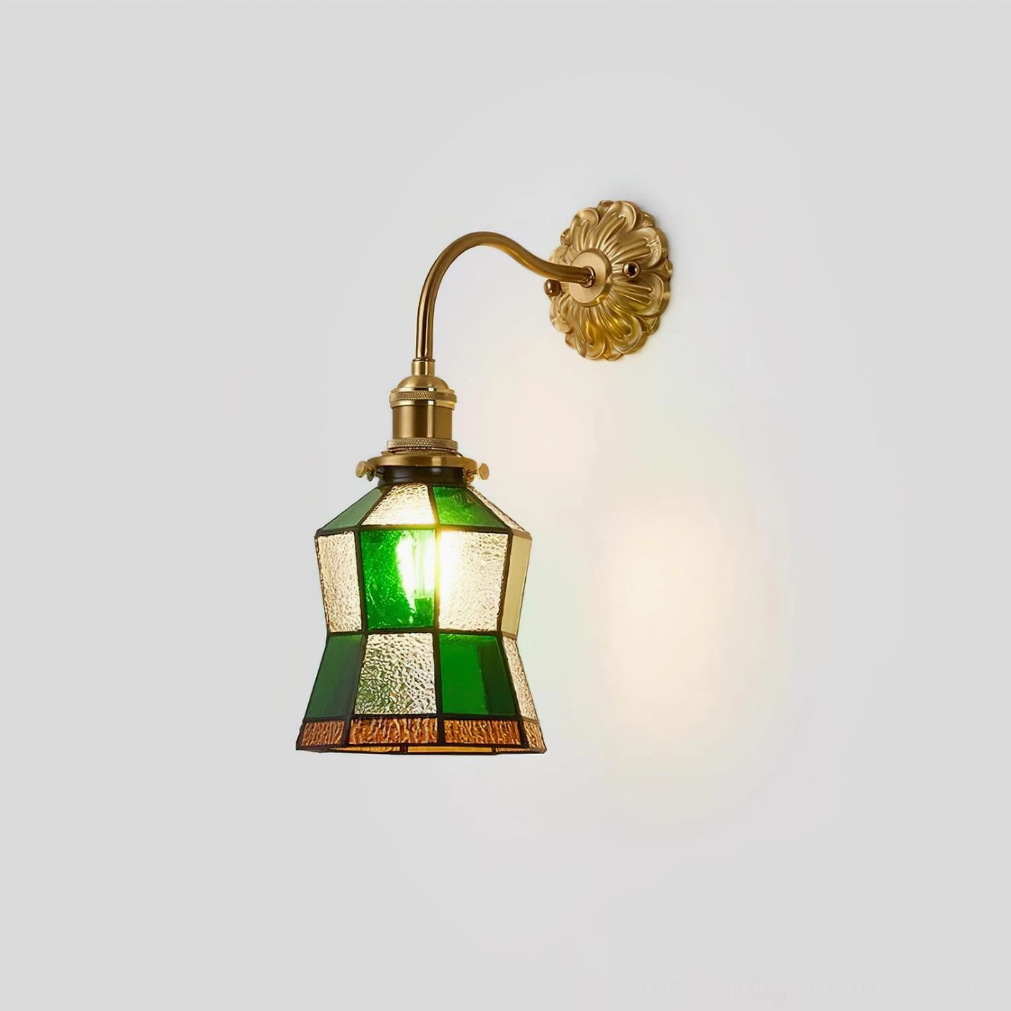 Stained glass wall lamp with curved brass arm and patchwork emerald and amber glass shade, shown from right front angle