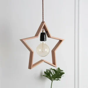 Star pendant light with warm natural wood tone and vintage-style bulb displayed against white wall with botanical decor