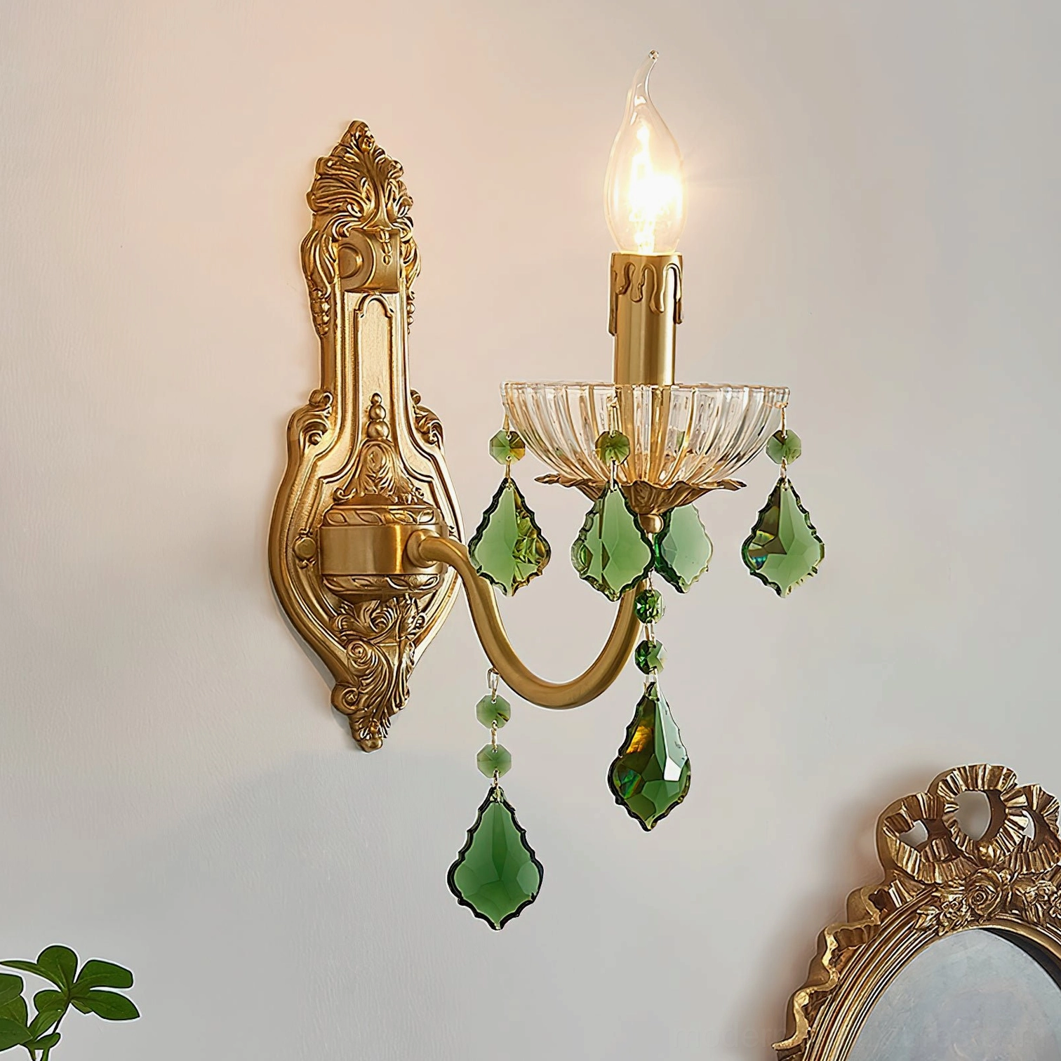Statement brass wall sconce with green crystal embellishments and vintage candle-style lighting