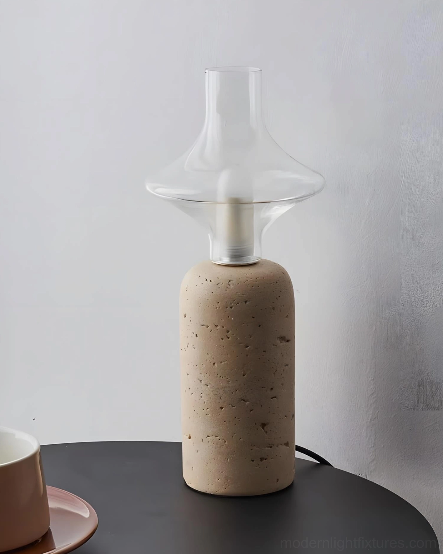 Beige travertine table lamp with glass chimney on bedroom bedside table creating cozy warm light
