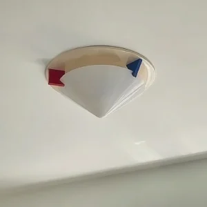 Stoja postmodern flush mount ceiling lamp side close-up detail showing translucent top frame with red and blue geometric color block accents against painted indoor wall