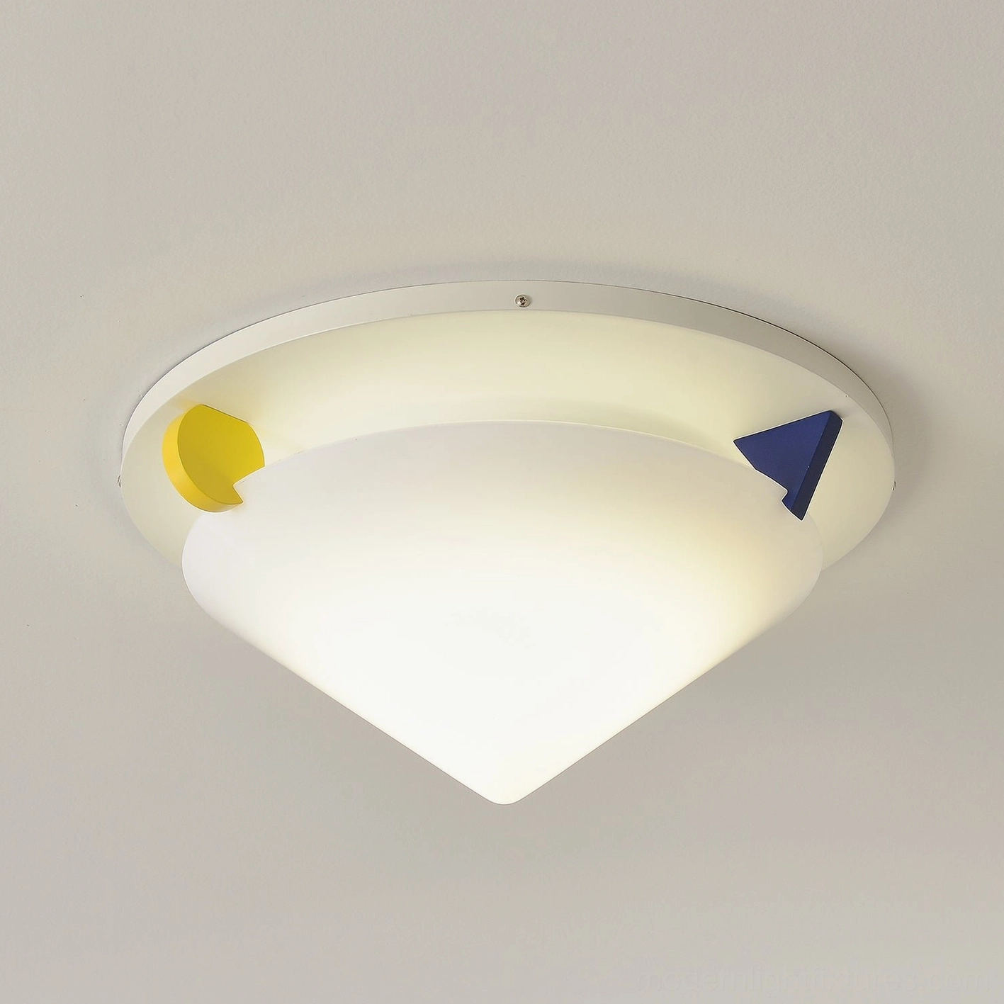 Stoja flush mount ceiling lamp close-up product shot warm lit lighting with yellow and blue geometric color block accents