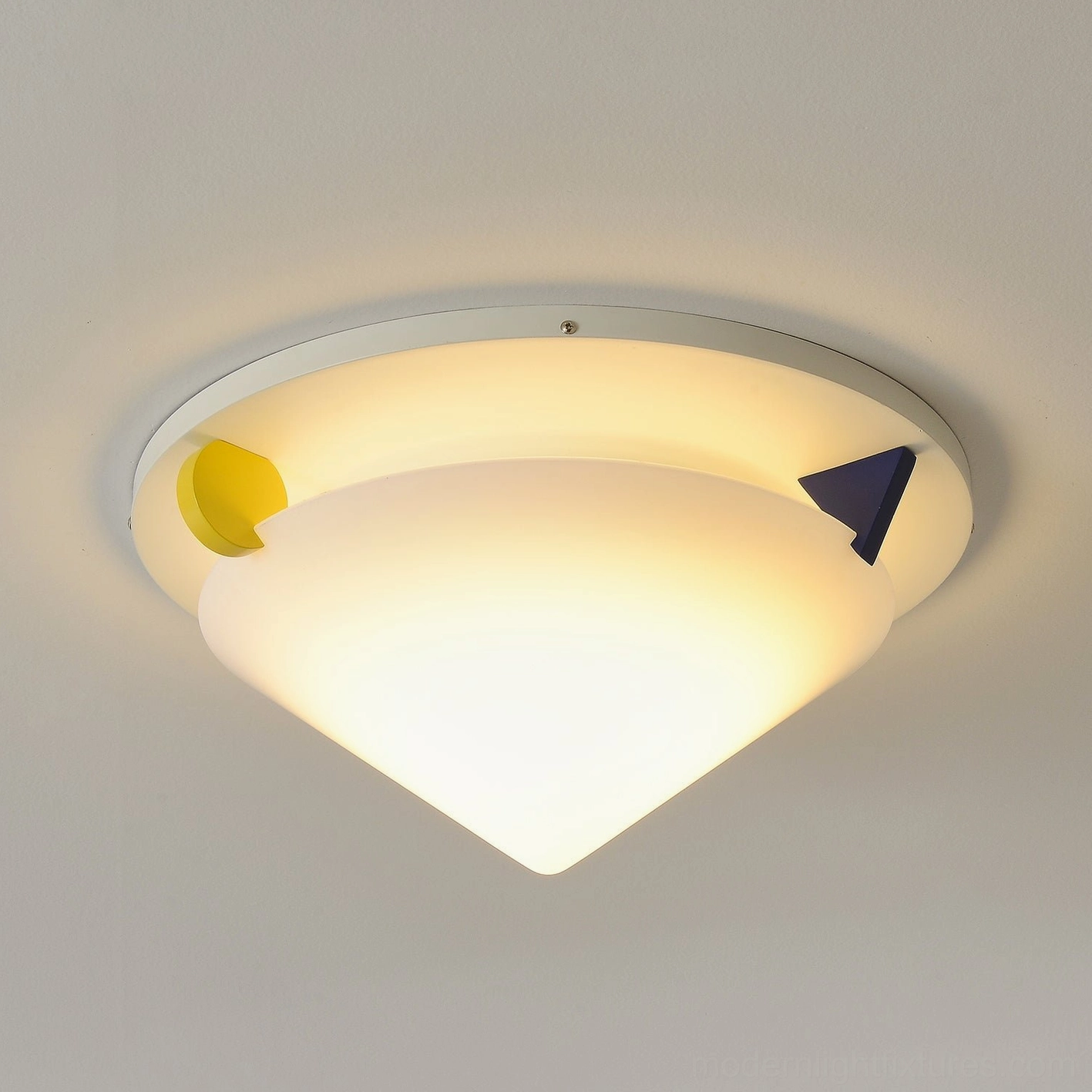 Stoja modern geometric ceiling lamp wide conical shade design warm lit lighting featuring yellow and blue Memphis style accent blocks