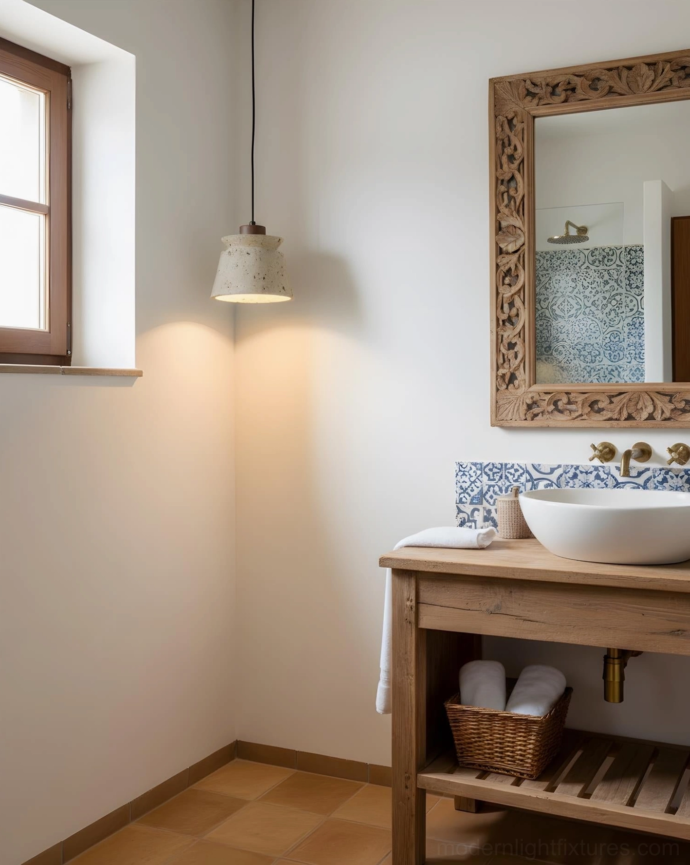 Farmhouse bathroom with travertine pendant light above wooden vanity and carved decorative mirror