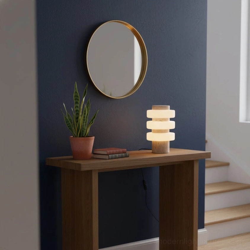 Contemporary strata table lamp on hallway console with dark blue wall, round mirror, and potted plant styling
