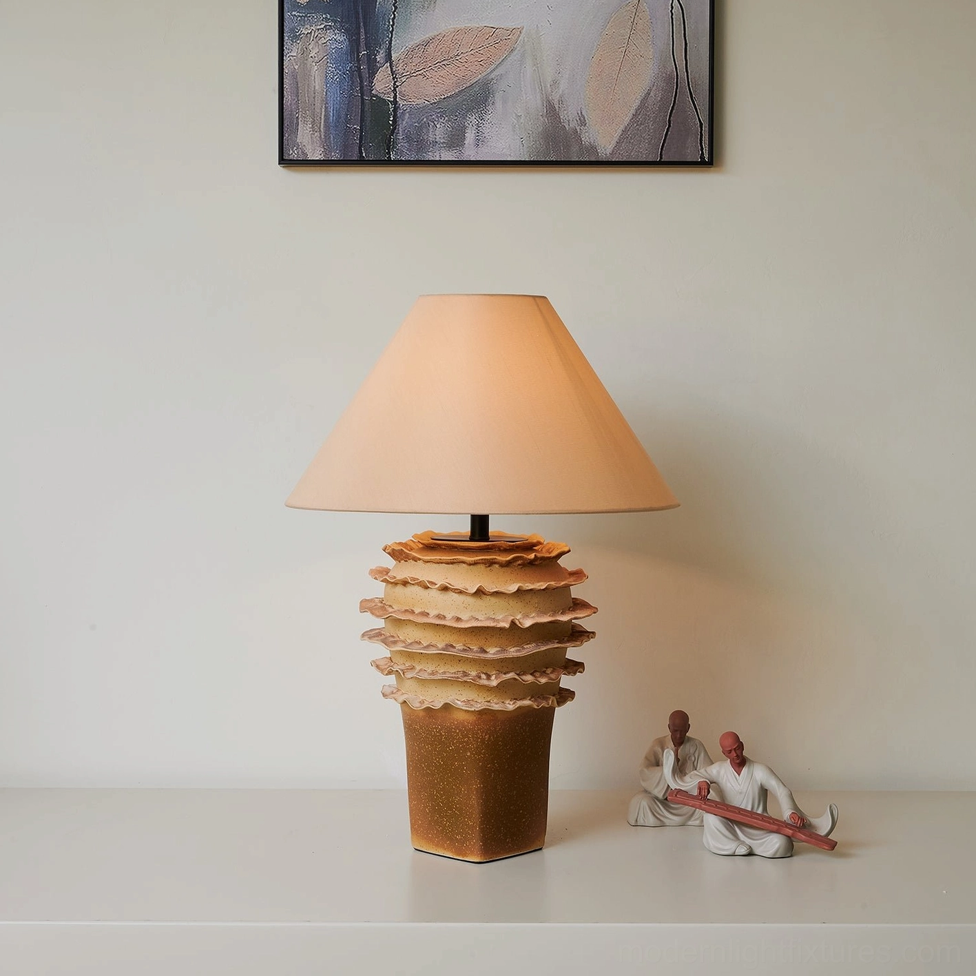 Modern organic ceramic table lamp with tiered base styled on tabletop with decorative figurines