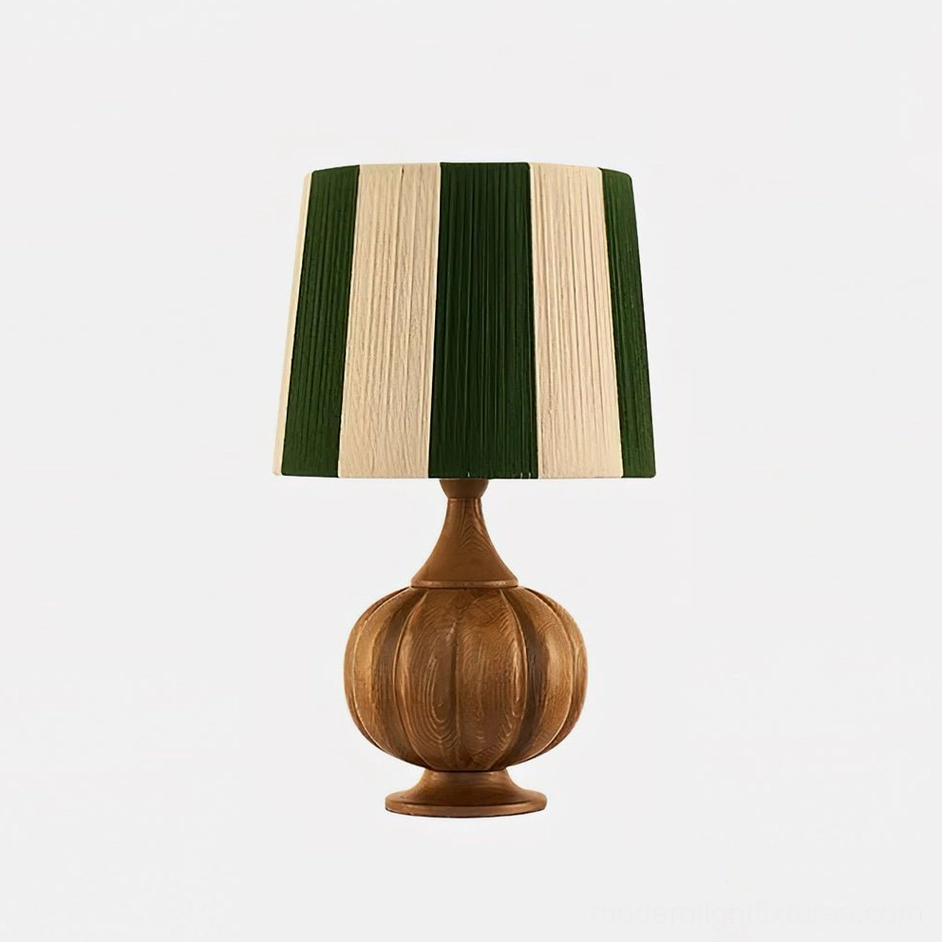 Wooden pumpkin base table lamp with striped shade in bright interior with sheer curtains and natural light
