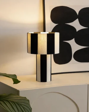Black and white striped modern table lamp, oblique angle view, minimalist interior design accent lighting