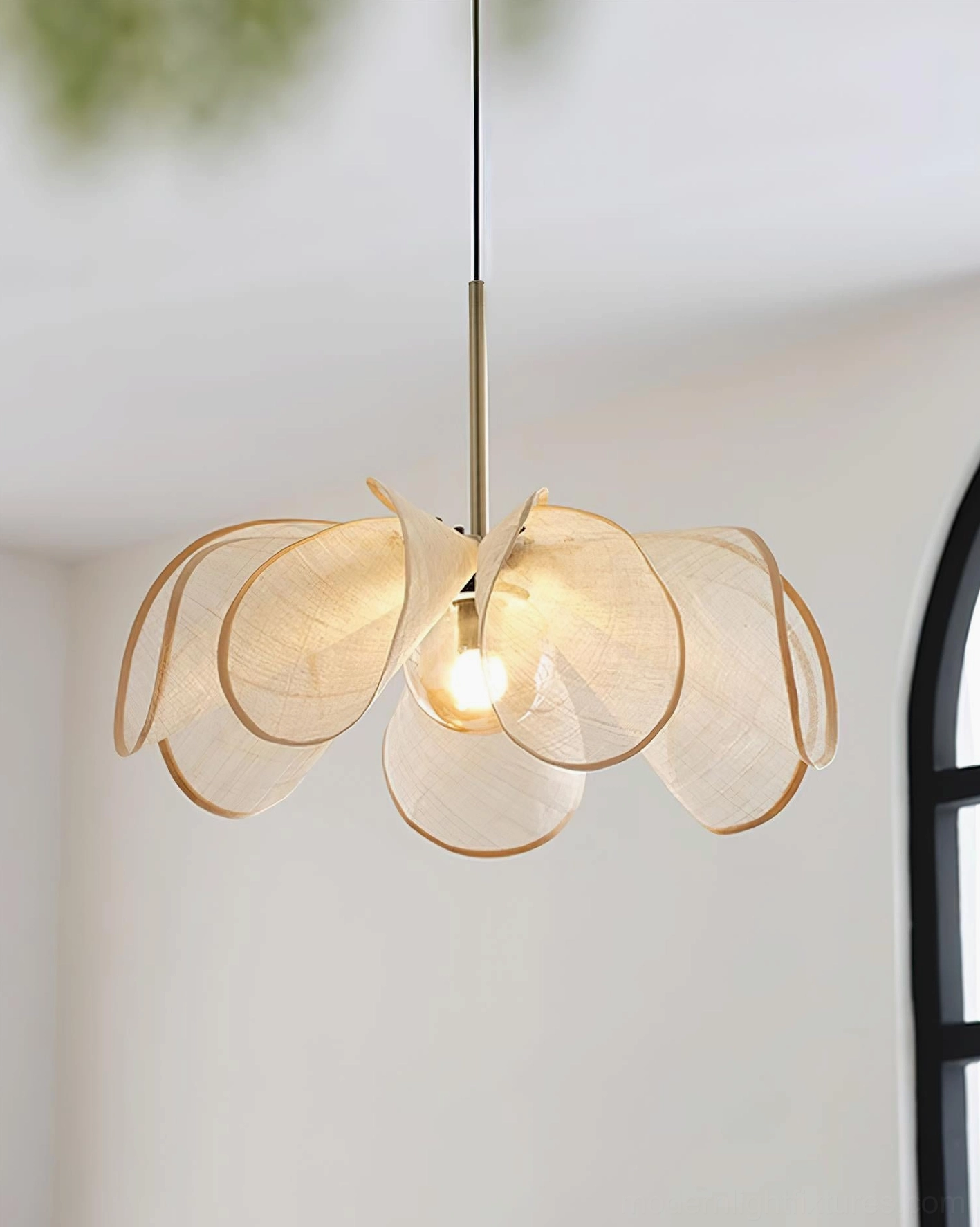 Organic petal-shaped pendant light in three-quarter angle showing beige jute fabric finish and warm bulb glow in contemporary home