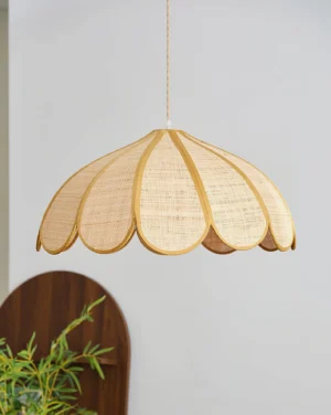 Scalloped woven pendant lamp displayed in modern home interior with wooden decor and green plant, three-quarter angle view