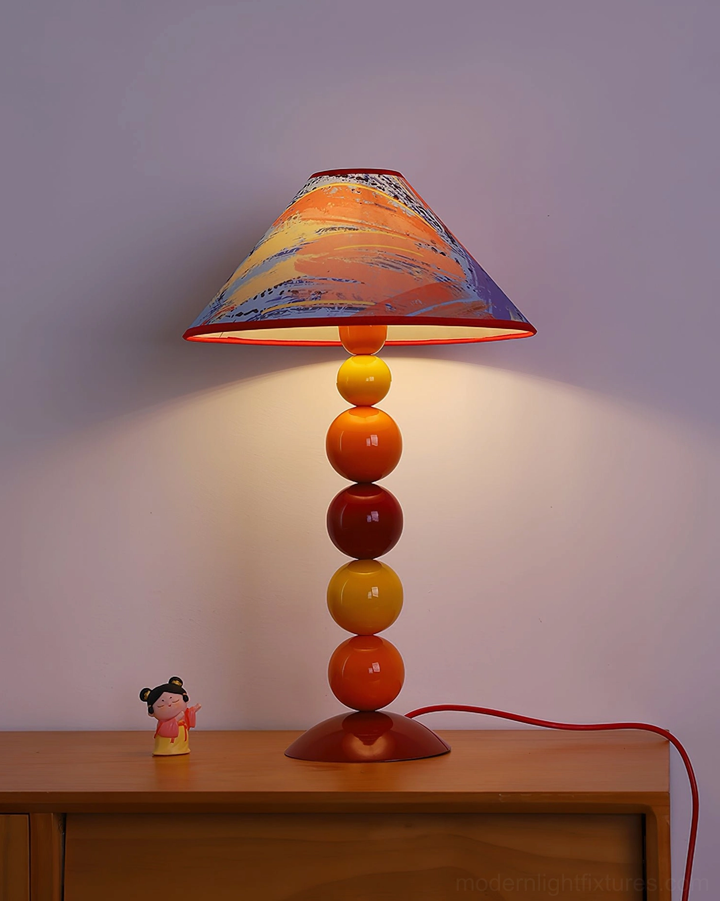 Illuminated colorful beaded table lamp on wooden side table with warm ambient glow and red cord - functional artistic home lighting