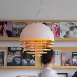 Sunset pendant light installed in Nordic style home study with bookshelf, matte white dome with warm orange interior layers