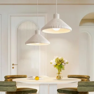 Two Surora pendant lights paired above round dining table in contemporary dining room with green velvet chairs