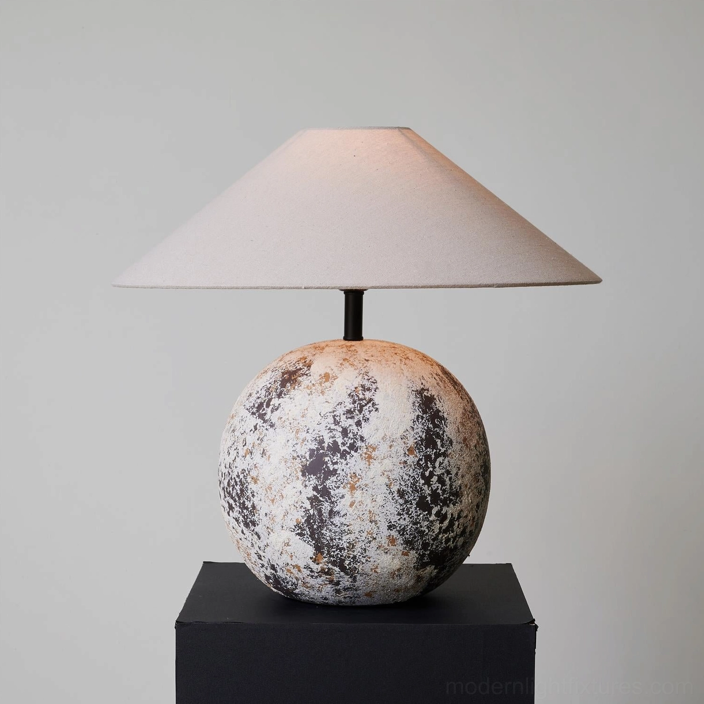 Left front three-quarter view of Surya ceramic table lamp showing detailed mottled texture and conical shade design on black plinth