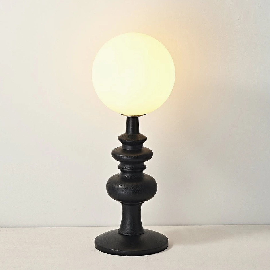 Sveta table lamp with matte black wood base and frosted glass globe - lit warm glowing shade